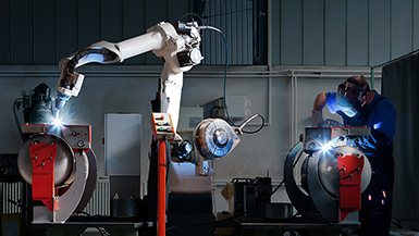 Cobot and welder working side-by-side in a dark room